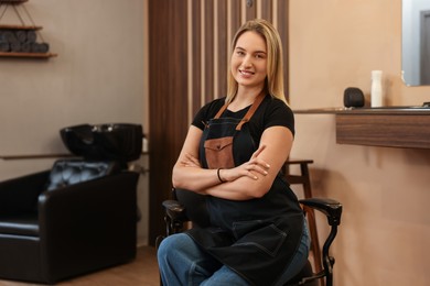 Photo of Portrait of professional hairdresser wearing apron in beauty salon