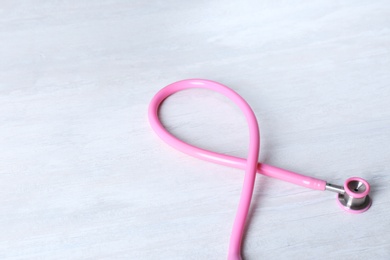 Photo of Pink stethoscope as awareness ribbon on light background. Breast cancer concept