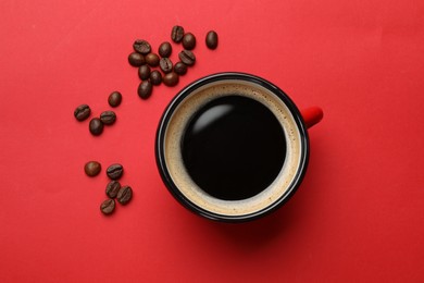 Photo of Fresh coffee in cup and roasted beans on red background, top view