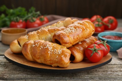 Delicious sausage rolls and ingredients on wooden table, closeup