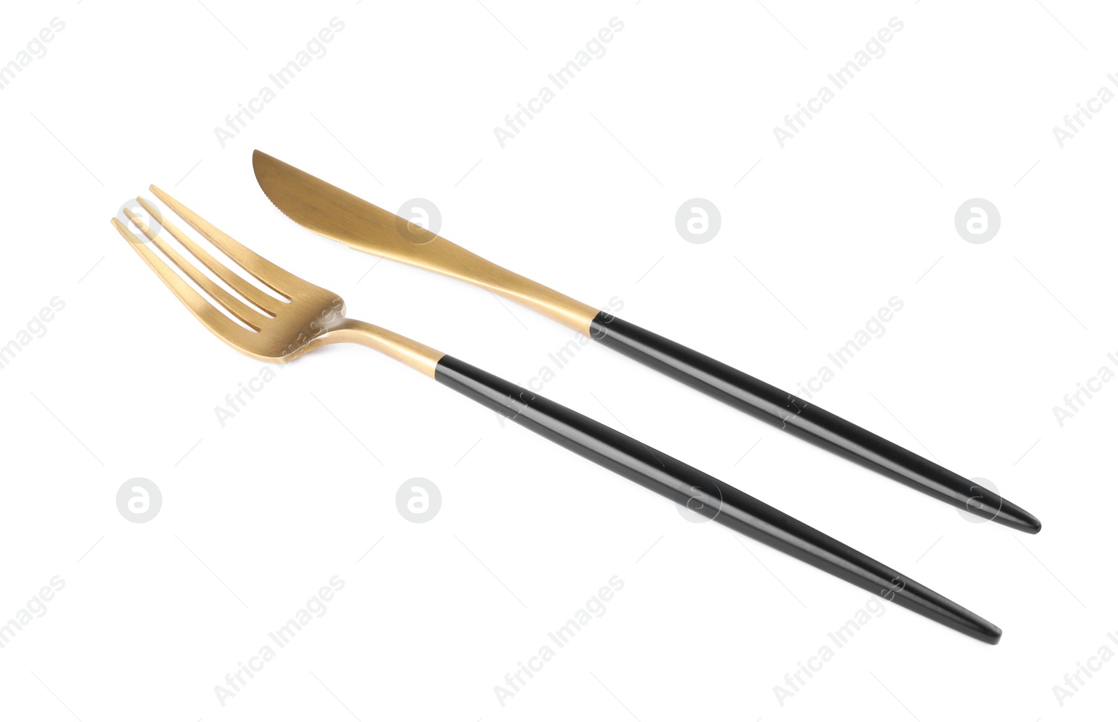 Photo of New golden fork and knife with black handles on white background