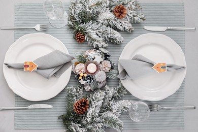 Photo of Festive place setting with beautiful dishware, cutlery and fabric napkins for Christmas dinner on grey table, flat lay