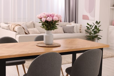 Photo of Table, chairs and vase with peonies in stylish dining room