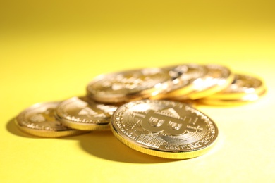 Shiny bitcoins on yellow background. Digital currency