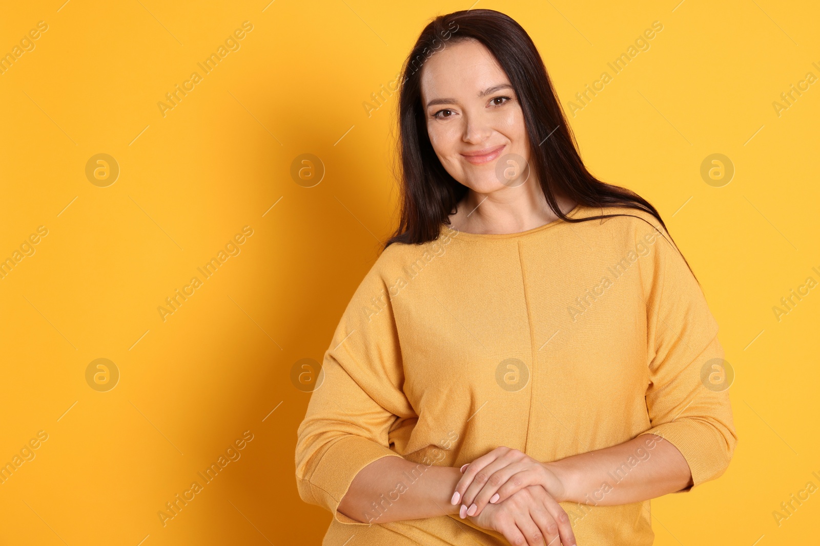 Photo of Beautiful overweight woman with charming smile on yellow background. Space for text