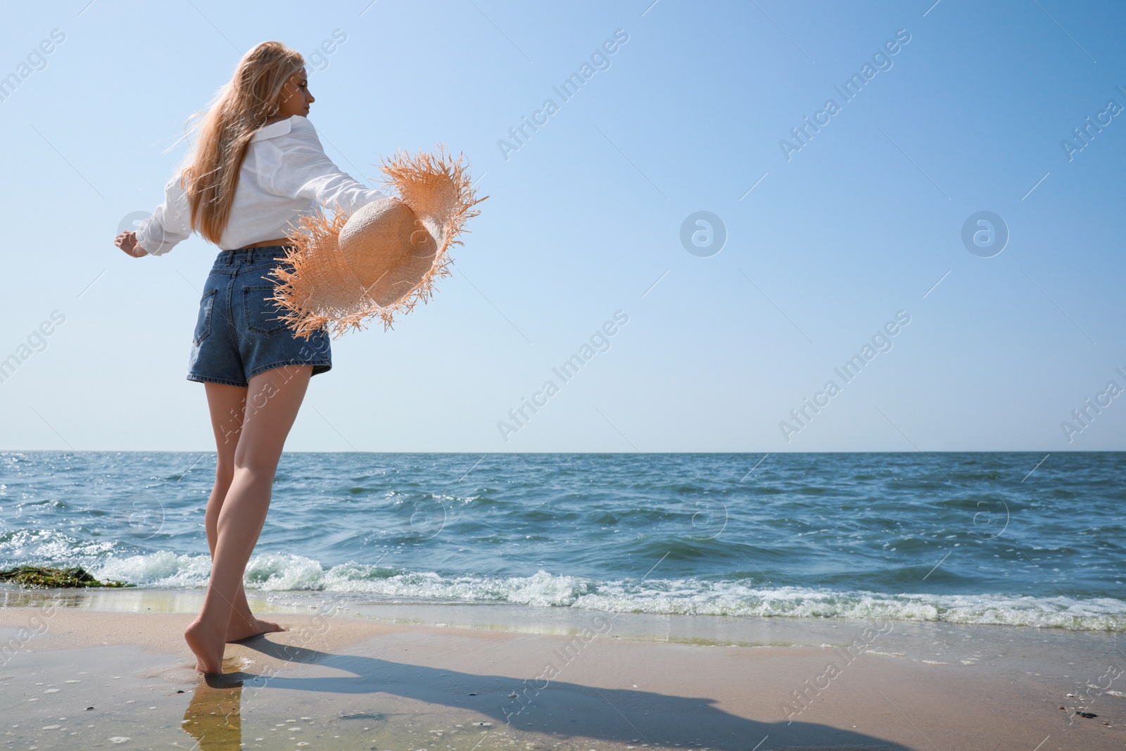 Photo of Young woman with straw hat near sea on sunny day in summer, low angle view