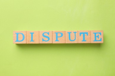 Photo of Word Dispute made with wooden cubes on light green background, top view