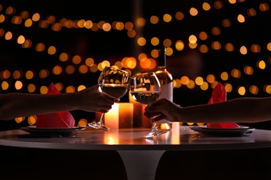 Photo of Young couple with glasses of wine having romantic candlelight dinner at table, closeup