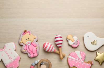 Cute tasty cookies of different shapes with toys and space for text on white wooden table, flat lay. Baby shower party