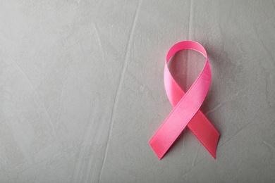 Pink ribbon on grey background, top view with space for text. Breast cancer awareness concept