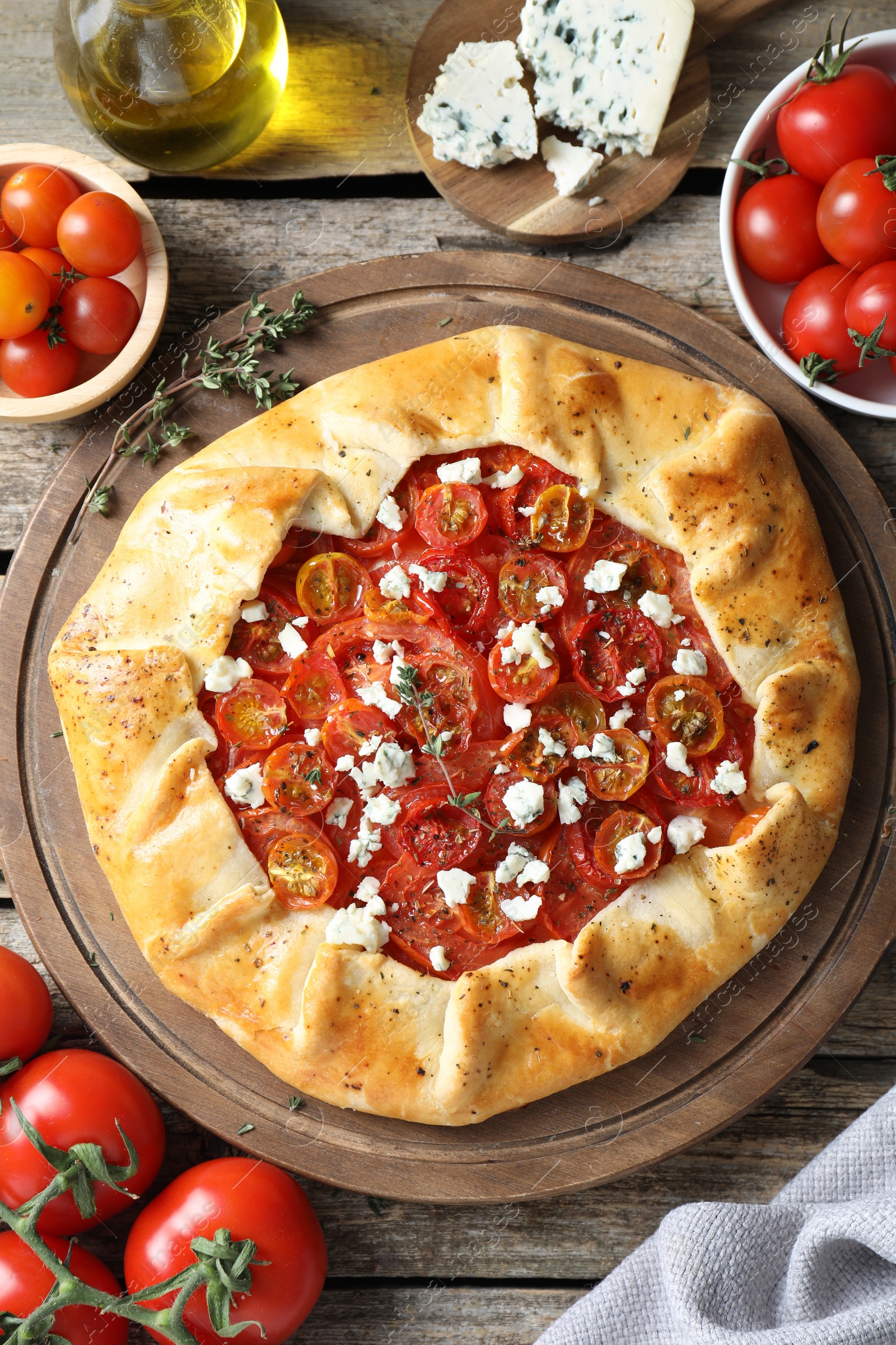 Photo of Flat lay composition of tasty galette with tomato, thyme and cheese (Caprese galette) on wooden table