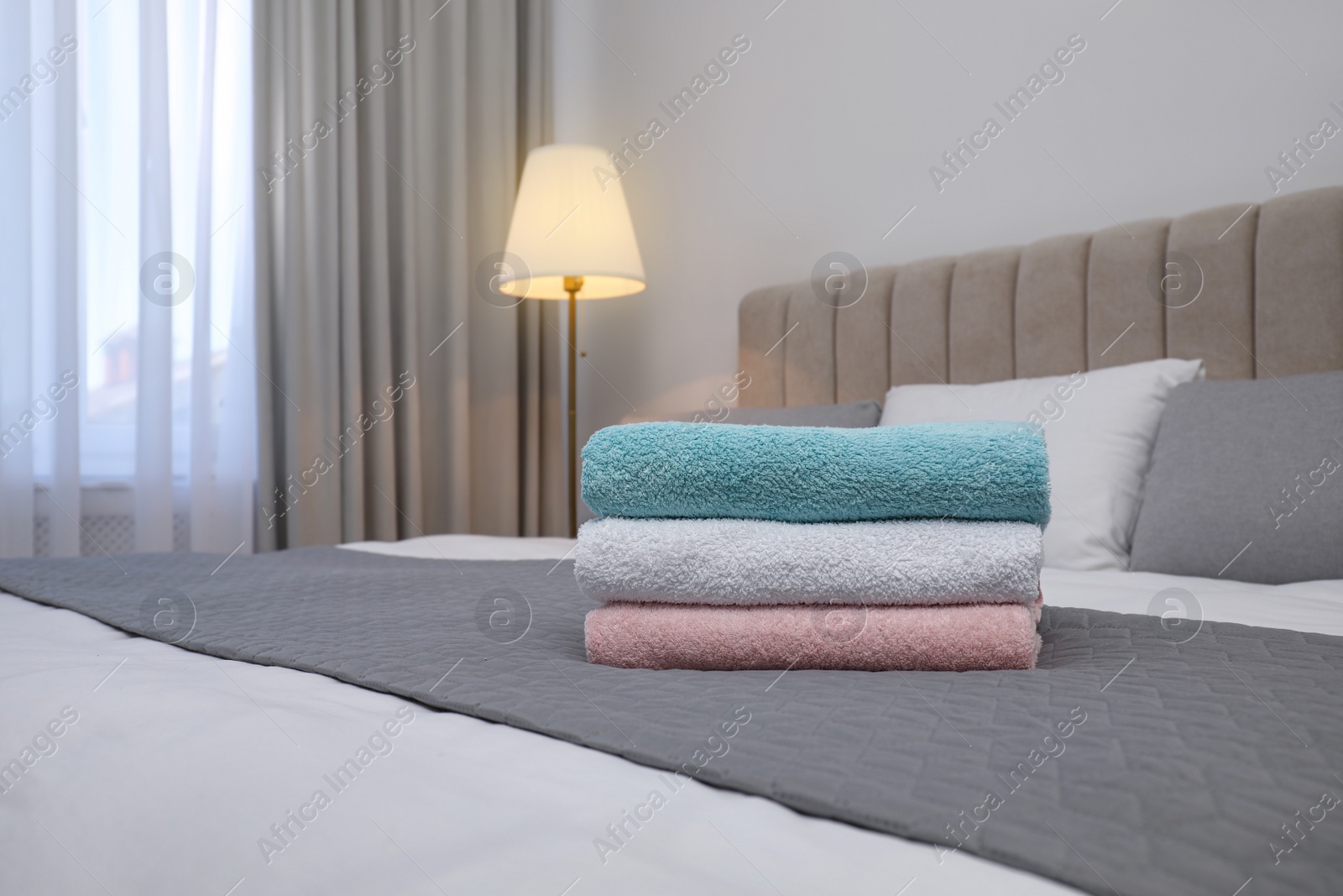 Photo of Stack of clean towels on bed indoors. Space for text