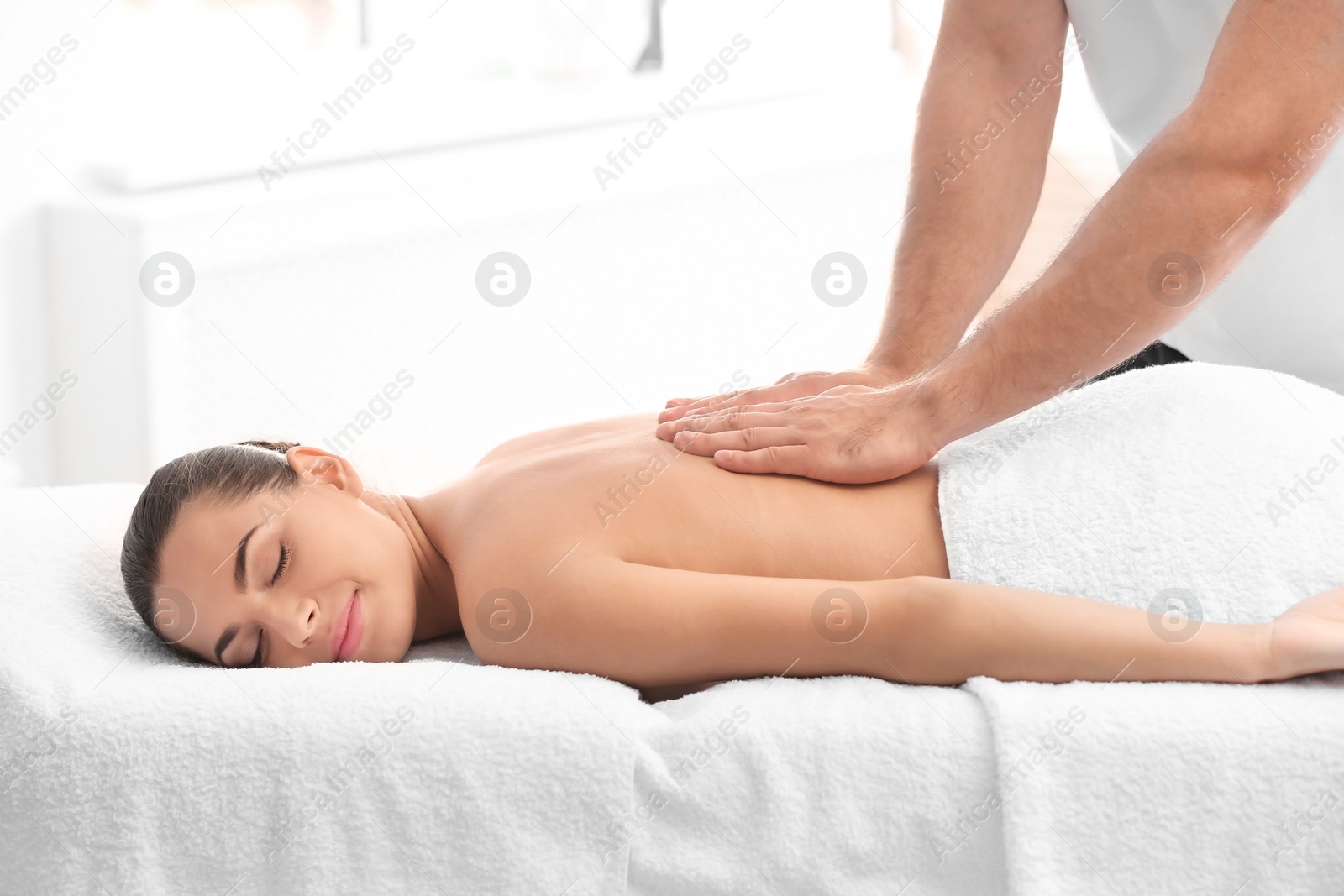 Photo of Relaxed woman receiving back massage in wellness center