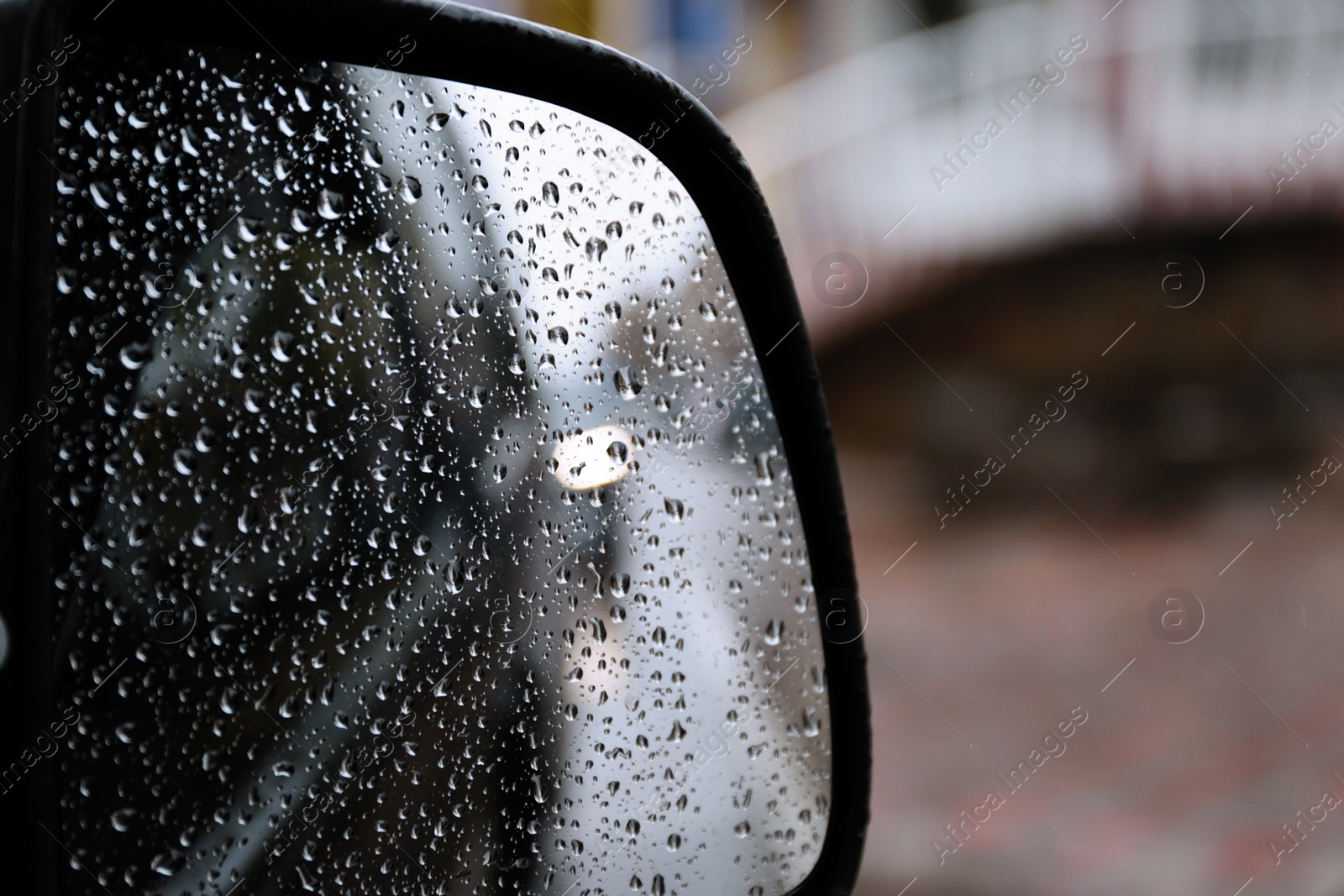 Photo of Closeup of car side rear view mirror with rain drops