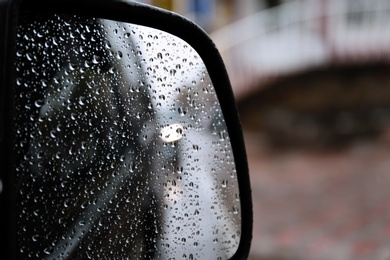 Closeup of car side rear view mirror with rain drops