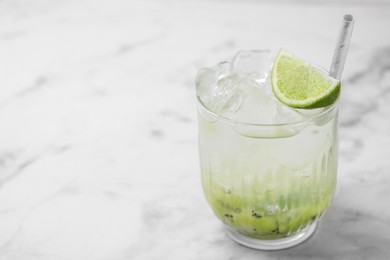 Glass of refreshing drink with kiwi and lime on white marble table, closeup. Space for text
