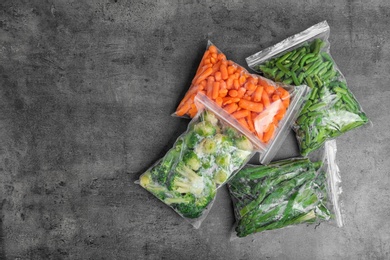 Plastic bags with different frozen vegetables on table, top view