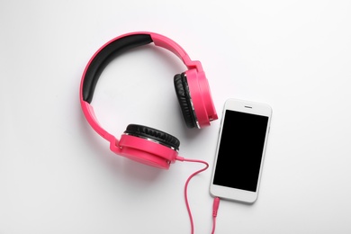 Photo of Stylish headphones and modern phone on white background, top view. Space for text