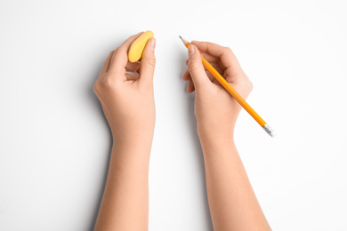 Photo of Woman holding pencil and eraser on white background, top view
