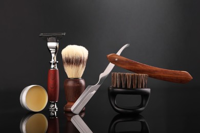 Photo of Moustache and beard styling tools on black mirror surface