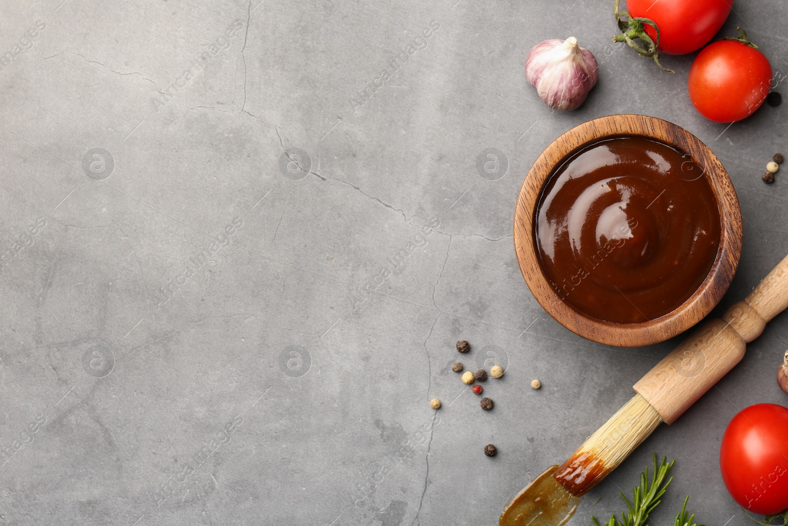 Photo of Flat lay composition with tasty barbeque sauce in bowl on grey textured table. Space for text