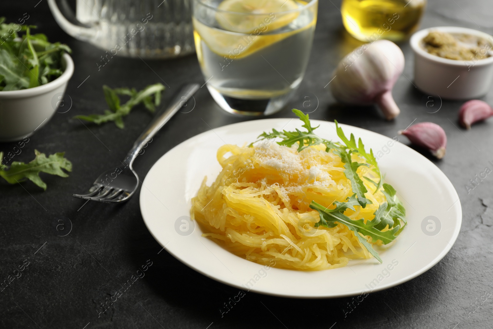 Photo of Tasty spaghetti squash with cheese and arugula served on black table