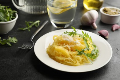 Photo of Tasty spaghetti squash with cheese and arugula served on black table