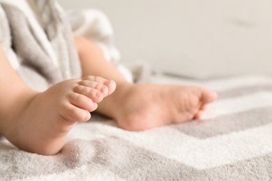 Little baby with cute feet on bed against light background, closeup. Space for text