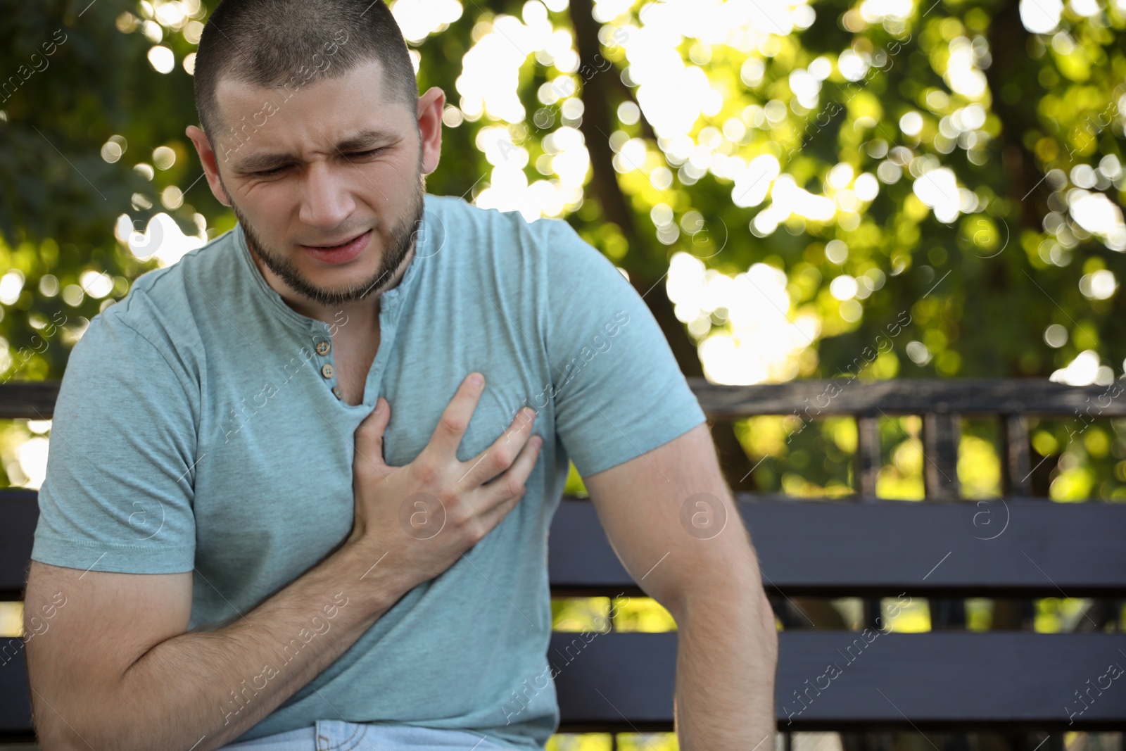 Photo of Man with heart attack sitting on bench in park