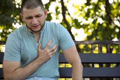 Man with heart attack sitting on bench in park