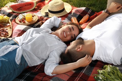 Photo of Happy young couple resting on picnic plaid outdoors