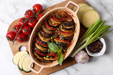 Photo of Delicious ratatouille and ingredients on white marble table, top view