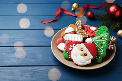 Different tasty Christmas cookies and decor on blue wooden table, space for text