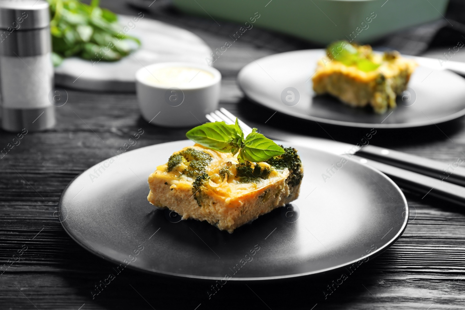 Photo of Tasty broccoli casserole served on black wooden table