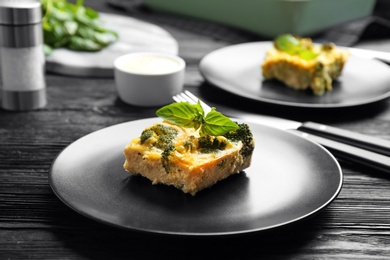 Photo of Tasty broccoli casserole served on black wooden table