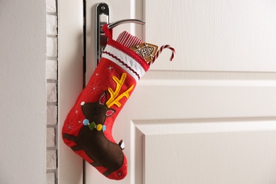 Photo of Stocking with presents hanging on door, space for text. Saint Nicholas Day tradition