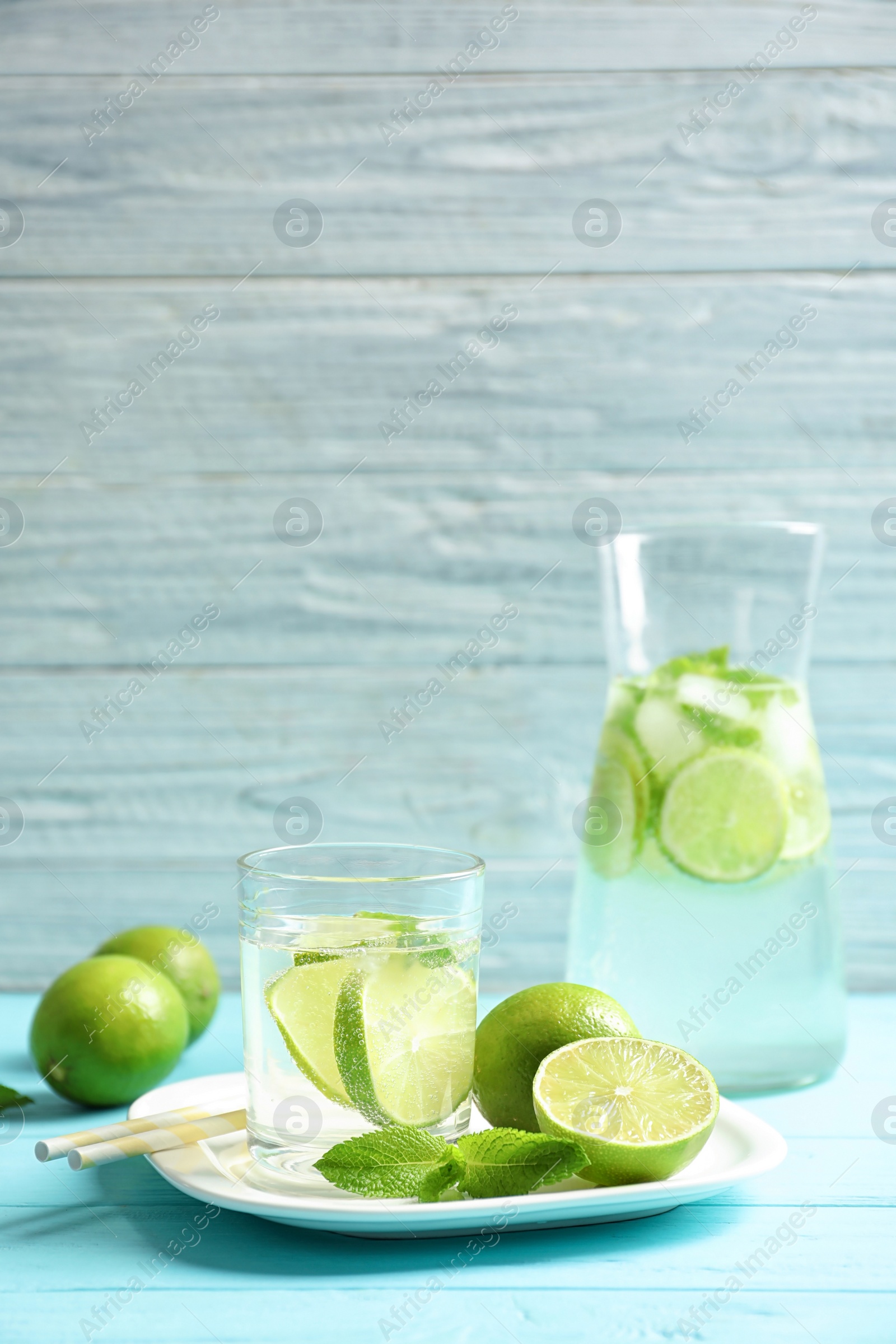 Photo of Natural lemonade with lime in glassware on wooden table