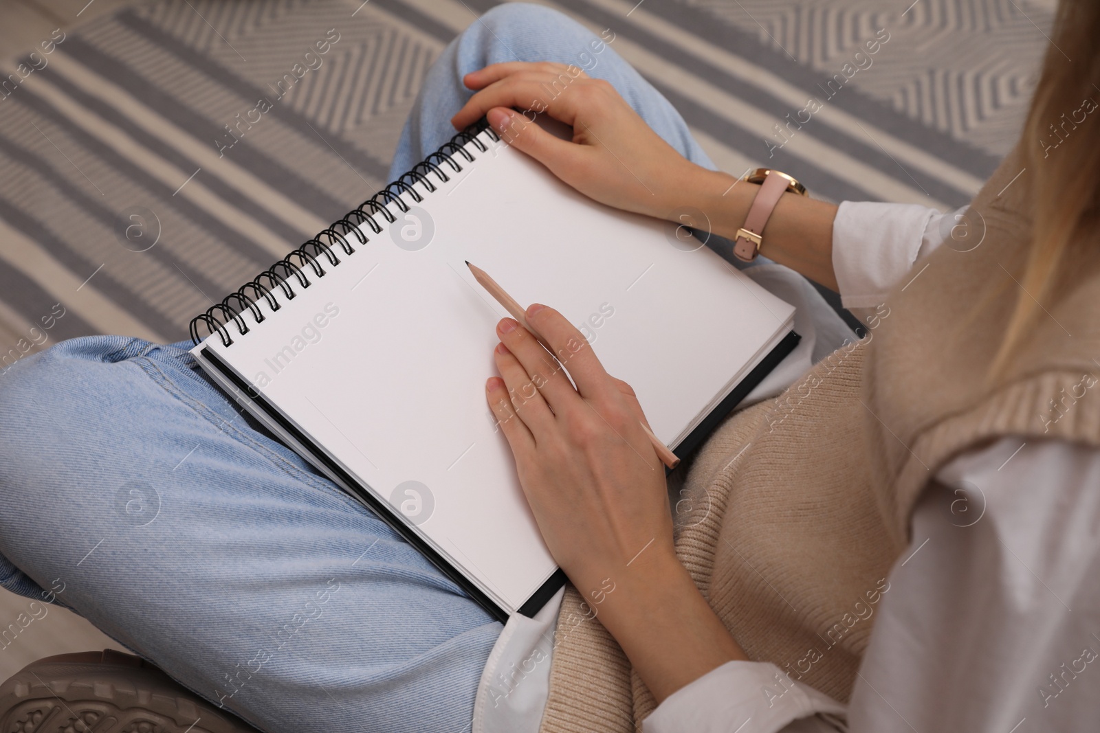 Photo of Woman drawing in sketchbook with pencil at home, closeup