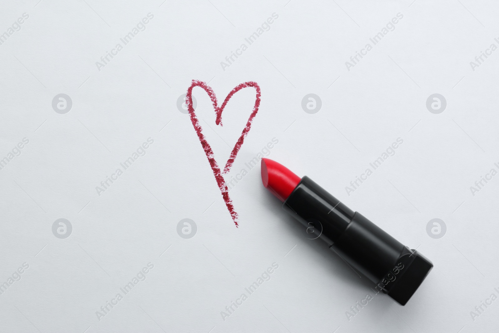 Photo of Red heart and lipstick on white background, top view