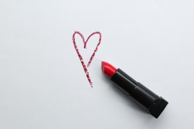 Photo of Red heart and lipstick on white background, top view