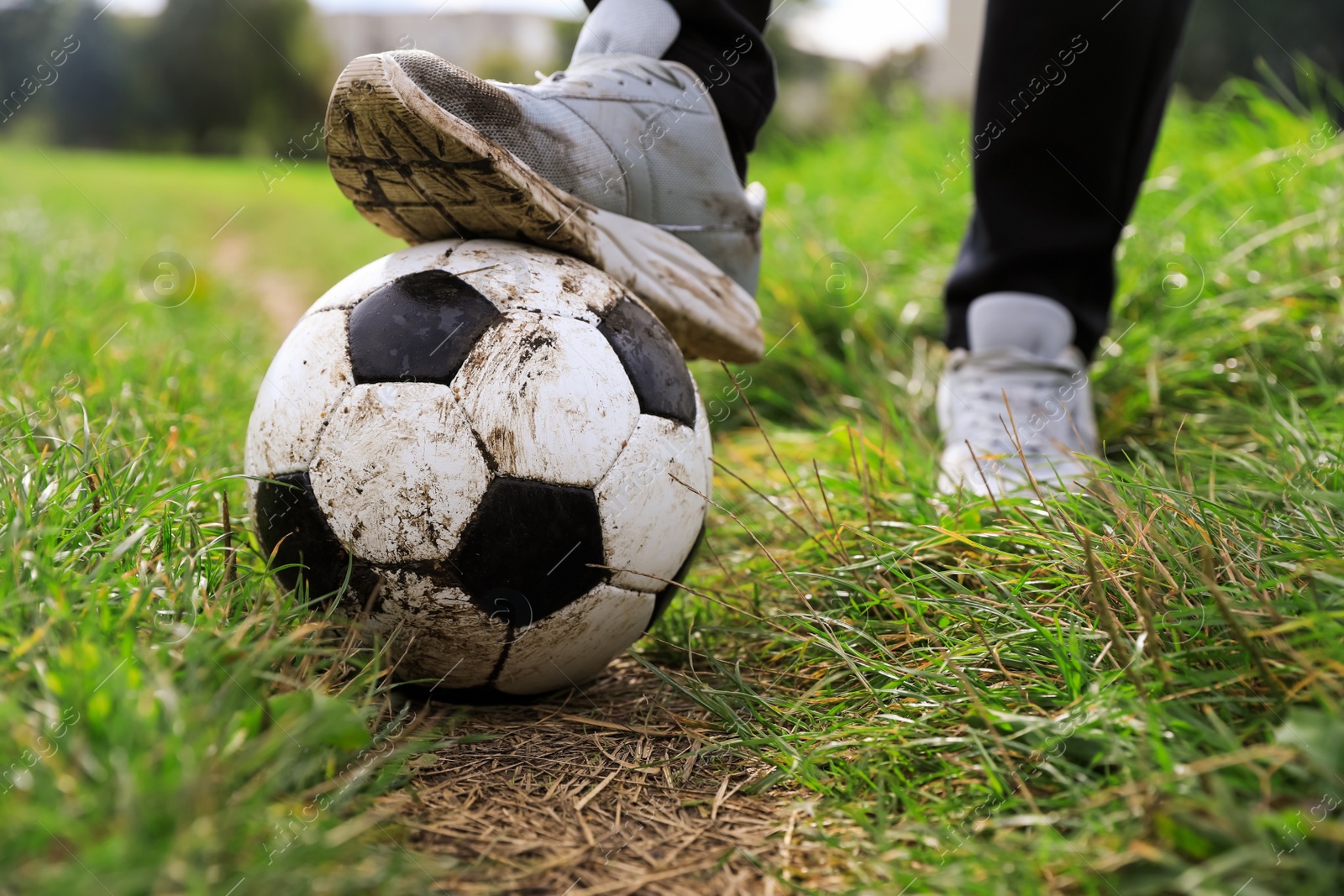 Photo of Man with dirty soccer ball outdoors, closeup