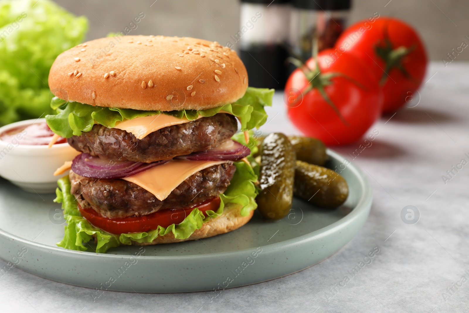 Photo of Tasty hamburger with patty, cheese and vegetables served on light gray table, closeup