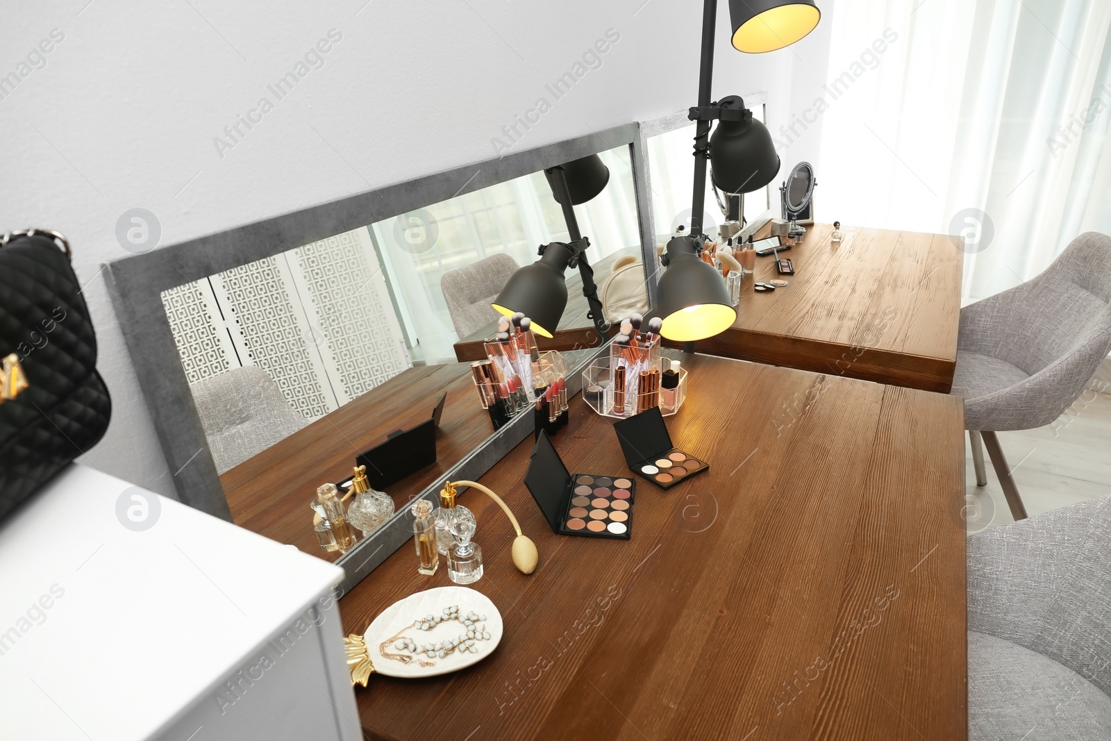 Photo of Cosmetic and brushes on dressing tables in makeup room