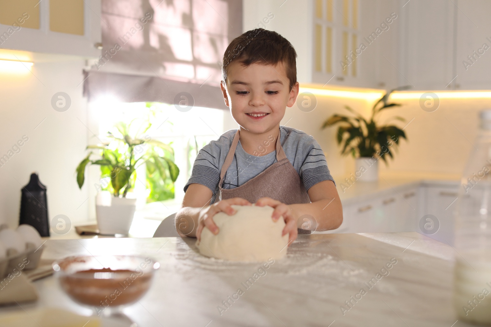 Photo of Cute little boy with dough at table in kitchen. Cooking pastry