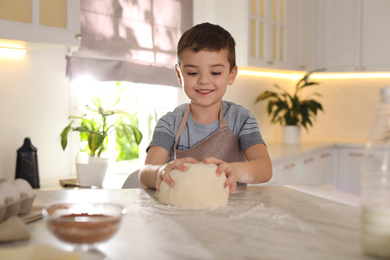 Cute little boy with dough at table in kitchen. Cooking pastry