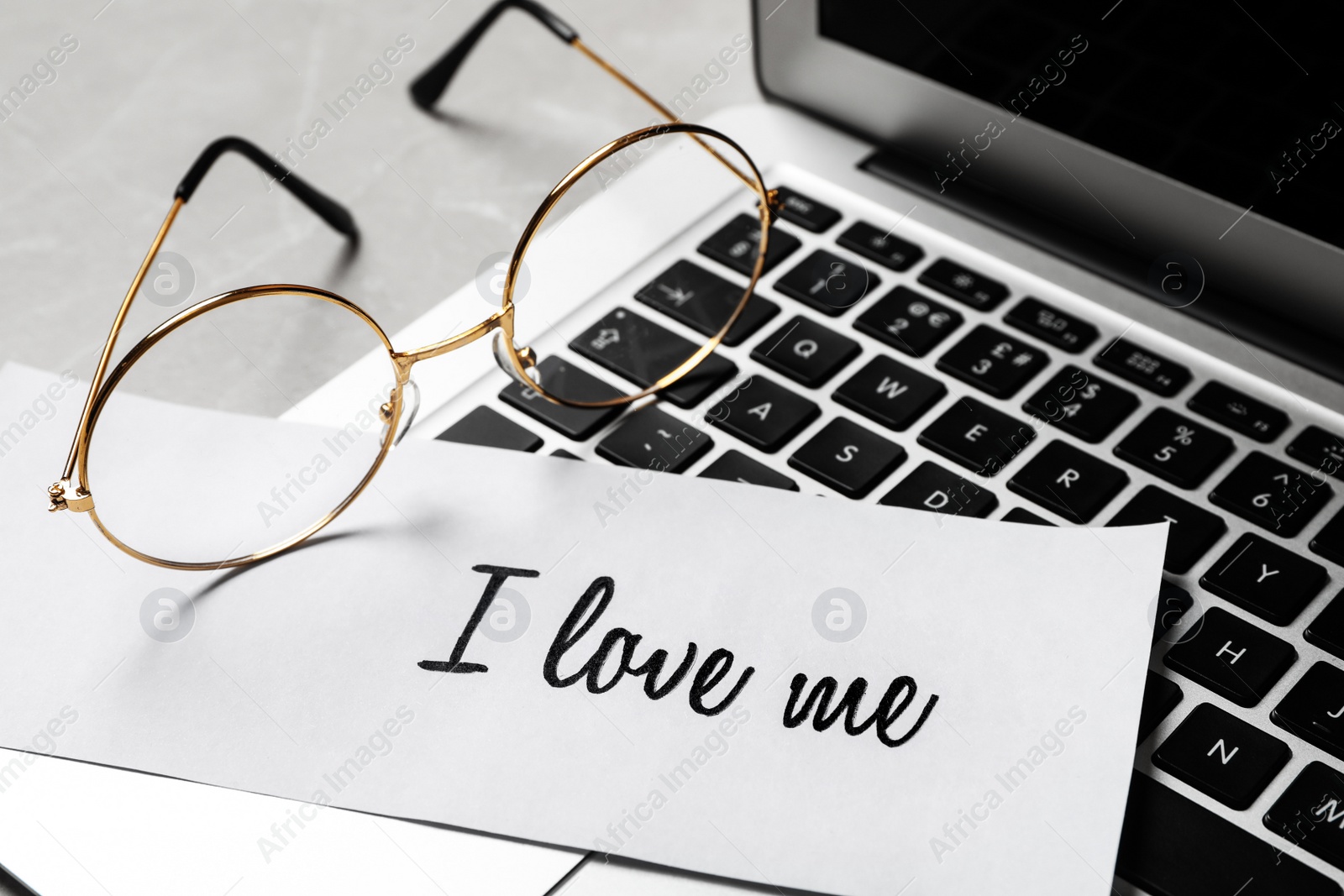 Photo of Paper with handwritten phrase I Love Me and glasses on laptop, closeup