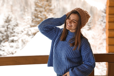 Photo of Pretty woman wearing warm sweater on terrace in winter