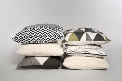 Photo of Stylish decorative pillows stacked on light background