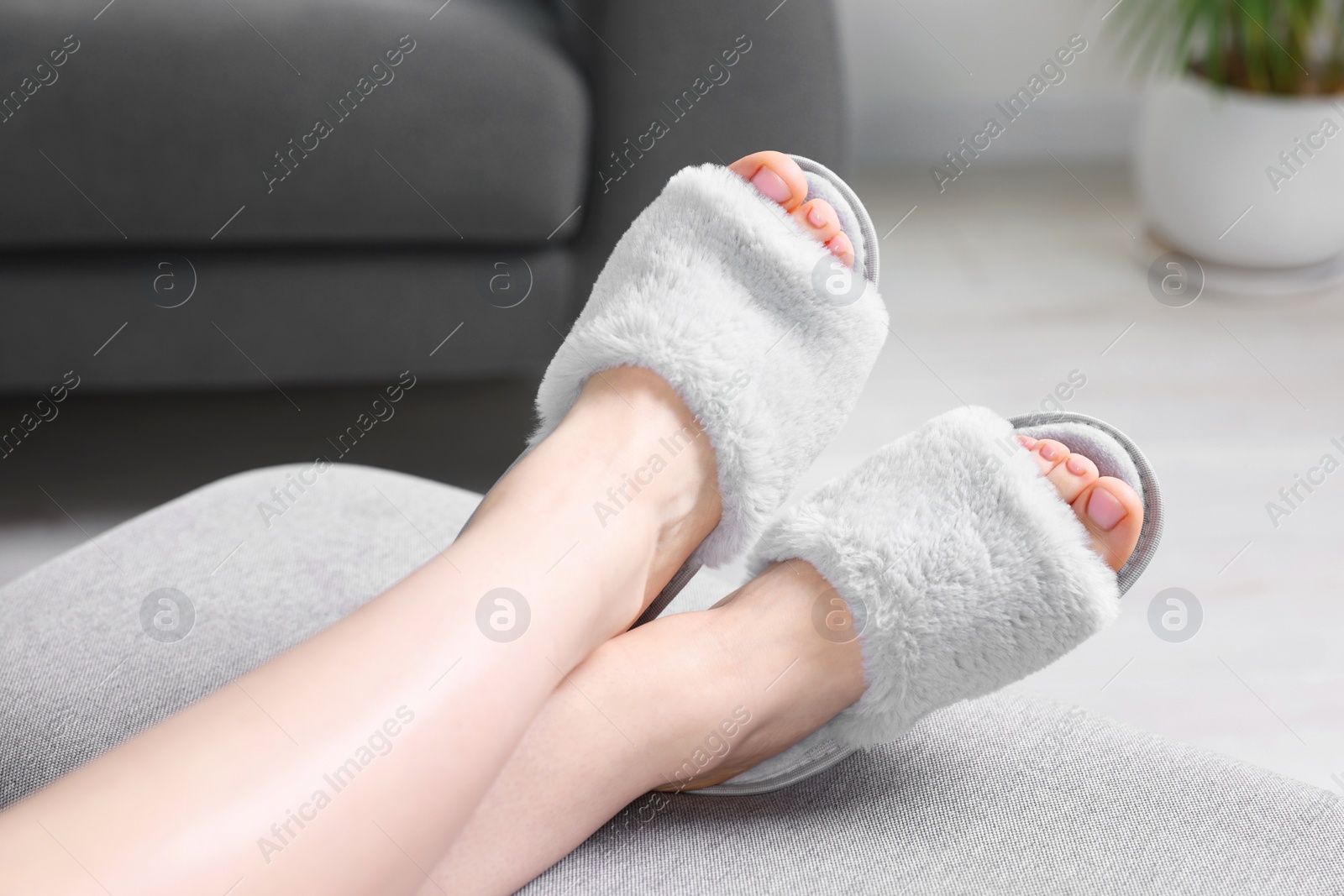 Photo of Woman in grey soft slippers resting at home, closeup