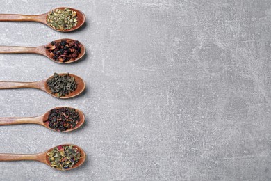 Photo of Flat lay composition with different teas and spoons on light grey stone table. Space for text